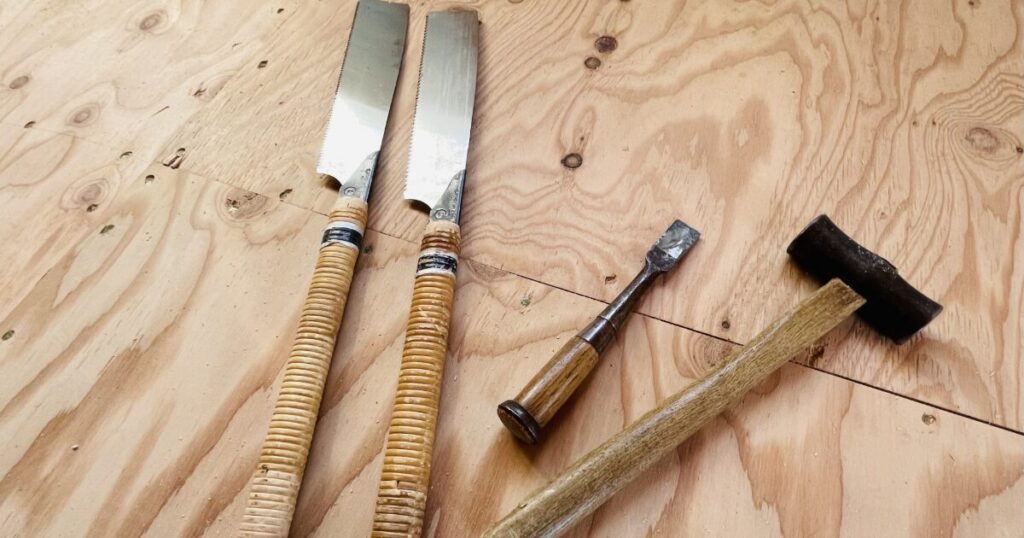 ノコギリとのみとハンマーを並べた木工用手工具