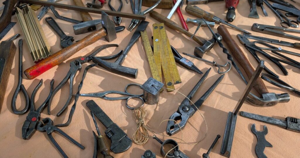 ハンマーやペンチなど多種類の手工具を並べた作業用品一式